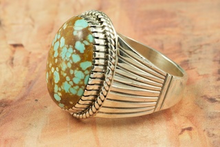 Genuine Number 8 Turquoise set in Sterling Silver Ring. The Number 8 mine is located in Eureka County Nevada. Since 1976 there has been no Number 8 Turquoise mined. There is however, an existing stock pile that Mr. Dowell Ward, the last owner of the Number 8 mine, had stocked away for later sorting. The Turquoise is a collector's item--because once the reserve is gone there will be no more material released onto the market. The Gold Mining Company owns the claim to the Number 8 mine and it has been swallowed up by the gold mining operations. This is some of the last Number 8 Turquoise to be had and will be a great addition to your collection. Created by Navajo Artist Larson Lee. Signed.
